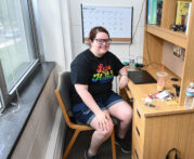 A female student sits at a desk smiling