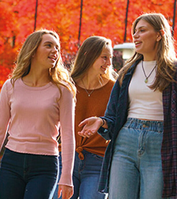 Three young women walking and talking to one another on campus