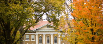 Photo shows Blaney Hall in the fall surrounded by trees with leaves turning orange and yellow