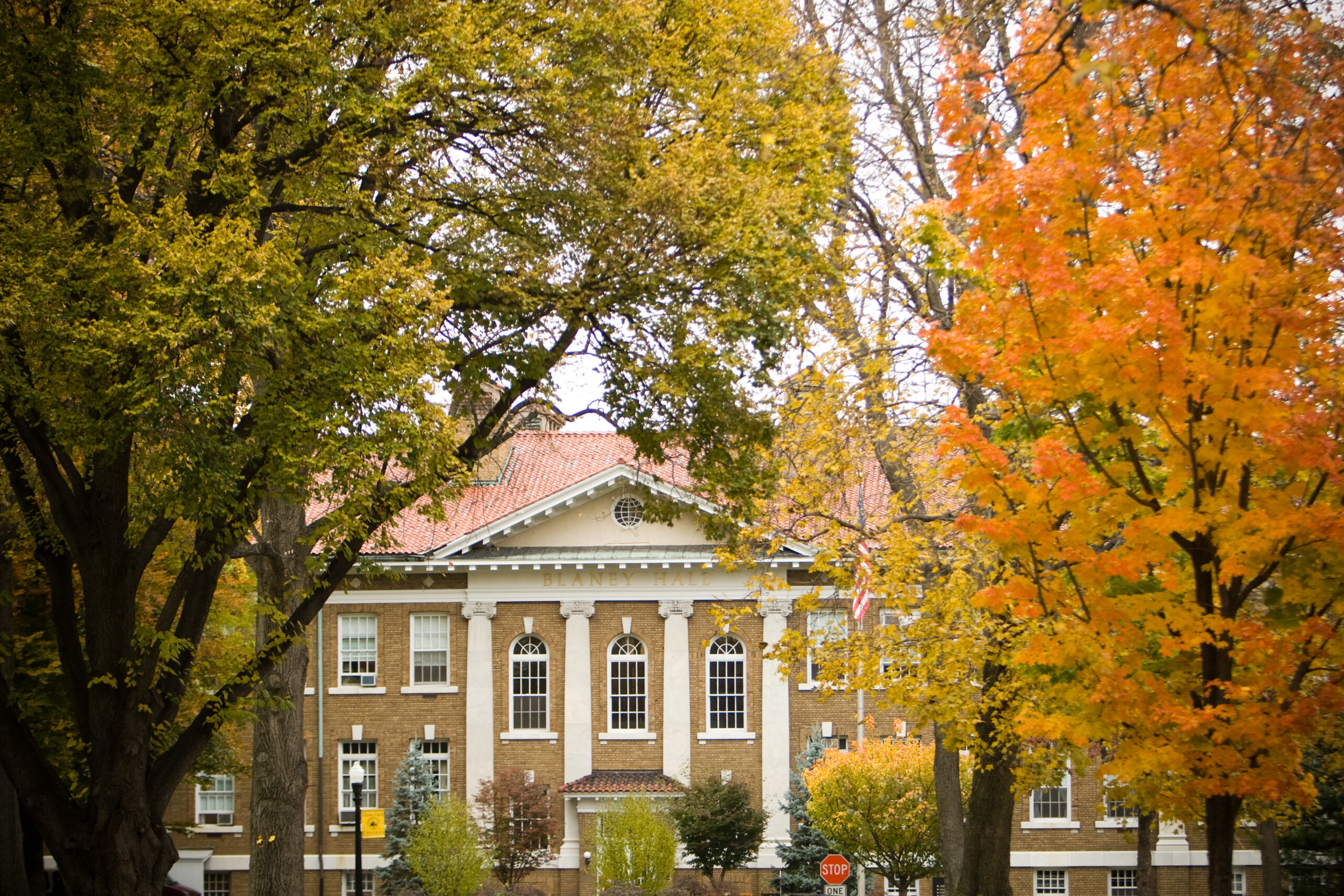 Photo shows Blaney Hall in the fall surrounded by trees with leaves turning orange and yellow
