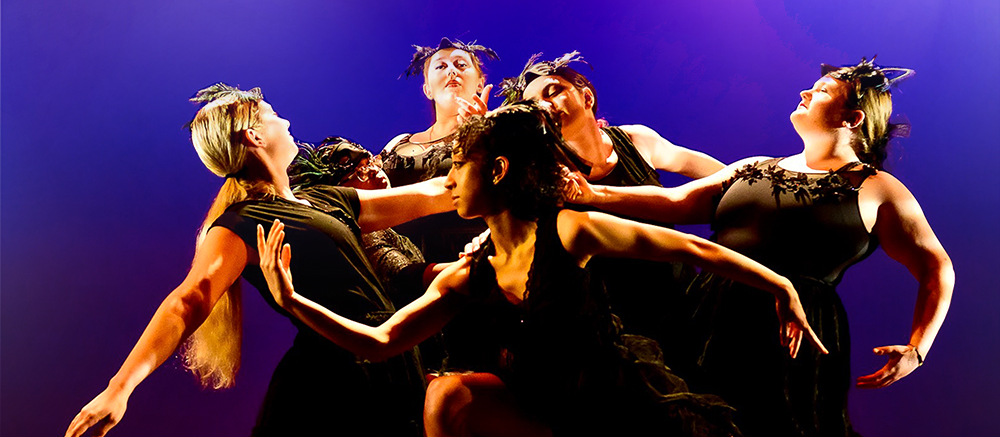 Students performing a dance in front of a purple backdrop