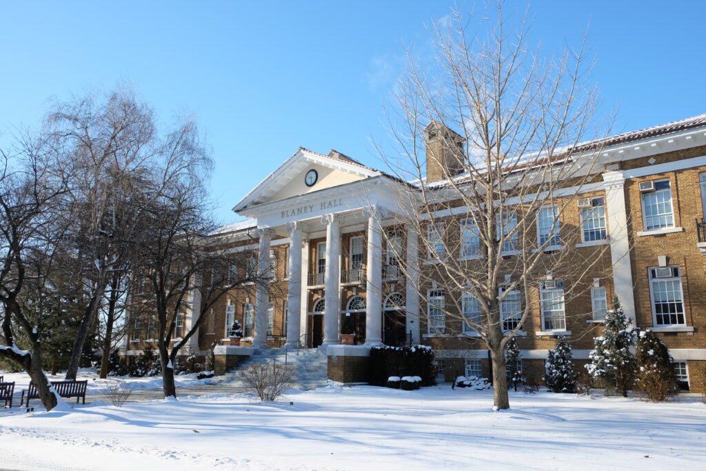 Blaney Hall in the winter, snow on the ground and bare trees on the lawn