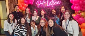 A group of students and staff standing in front of a pink balloon arch and a neon sign that says PA latina
