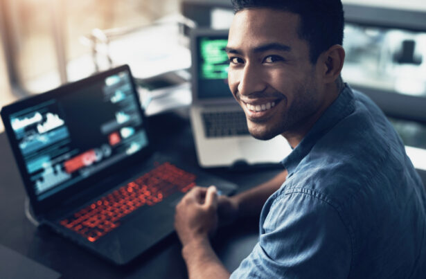 Portrait of a young man using a laptop in a modern office.